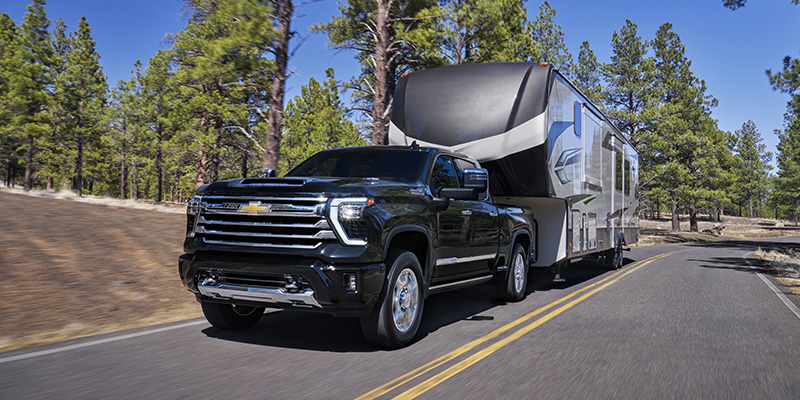 Chevrolet Silverado 2500HD towing a recreational vehicle on a highway, showcasing its powerful towing capability.